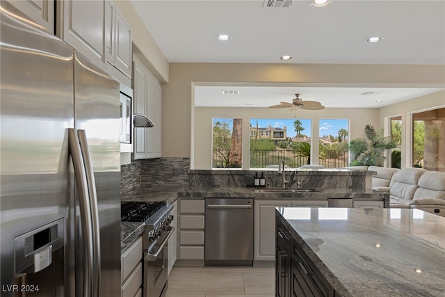 kitchen with stainless steel appliances, dark stone countertops, plenty of natural light, and sink