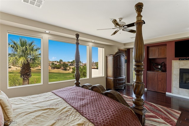 bedroom with a fireplace, dark wood-type flooring, and ceiling fan