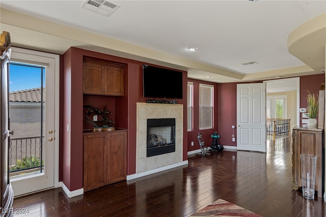 living room featuring dark wood-type flooring and a tiled fireplace