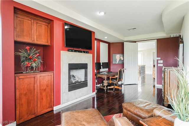 living room featuring dark hardwood / wood-style floors and a tiled fireplace