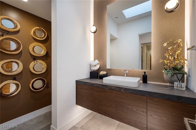 bathroom with wood-type flooring, vanity, and a skylight