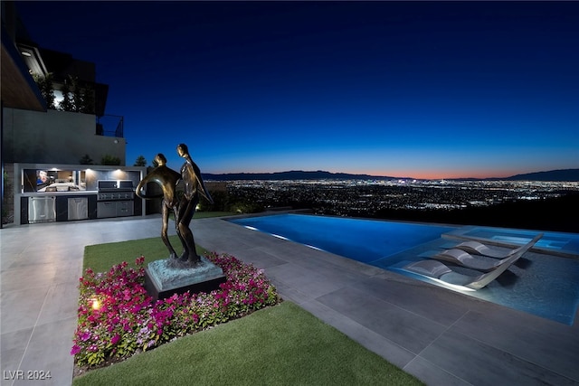 pool at dusk with a patio area, area for grilling, and a mountain view