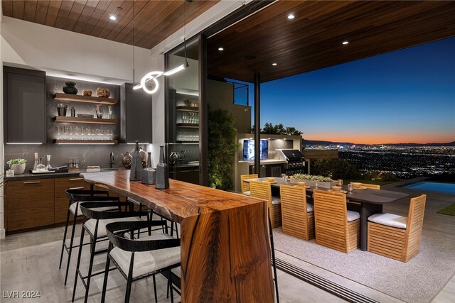 bar featuring dark brown cabinetry, sink, backsplash, and wood ceiling