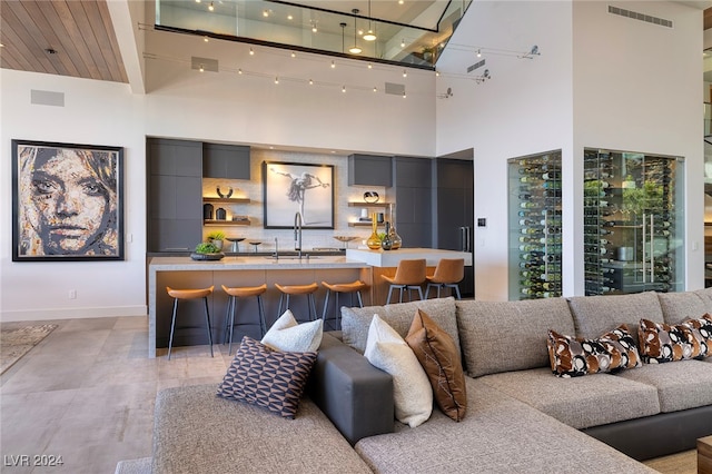 living room featuring a towering ceiling, sink, and beam ceiling