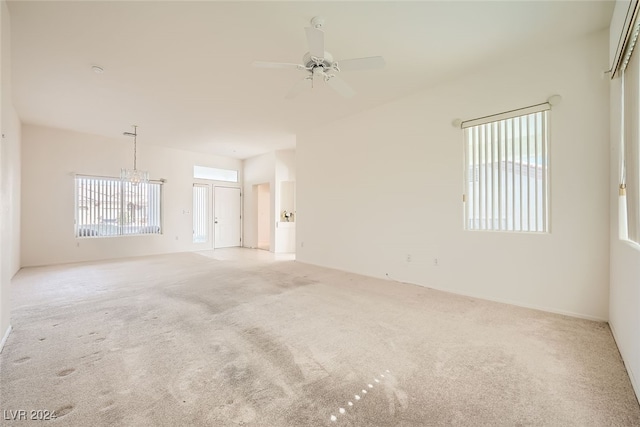 spare room with light carpet and ceiling fan with notable chandelier