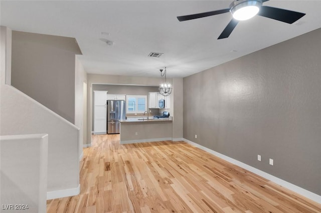 interior space with baseboards, visible vents, light wood-type flooring, a sink, and ceiling fan with notable chandelier