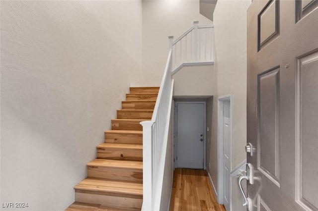 staircase featuring wood finished floors and a towering ceiling