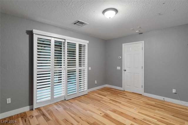 unfurnished room with wood finished floors, visible vents, and baseboards