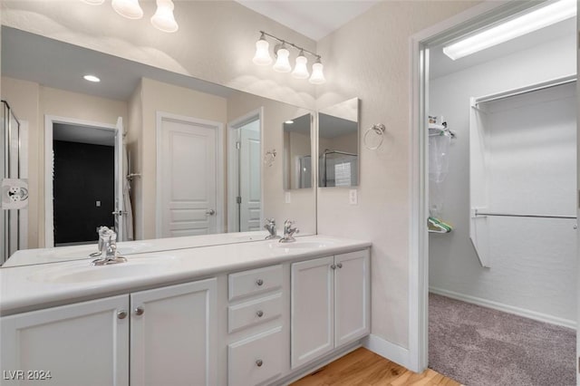 full bathroom with double vanity, wood finished floors, a sink, and baseboards