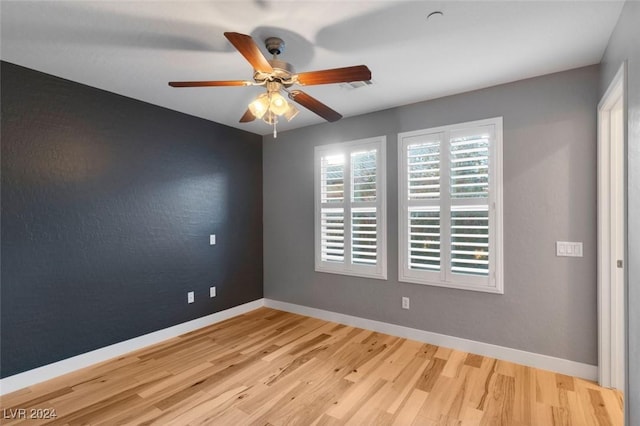 unfurnished room with ceiling fan, visible vents, baseboards, and wood finished floors