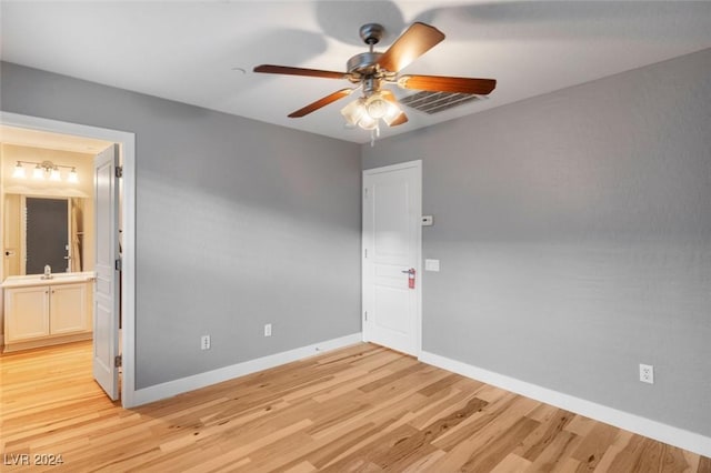 spare room featuring ceiling fan, a sink, visible vents, baseboards, and light wood finished floors