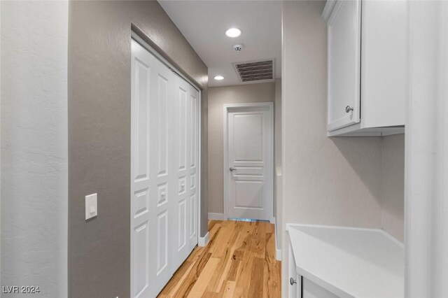 corridor featuring light wood-style flooring, visible vents, baseboards, and recessed lighting