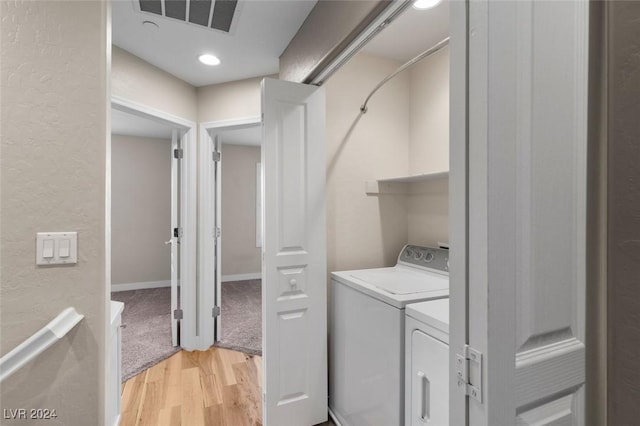 laundry area with laundry area, visible vents, a textured wall, washing machine and clothes dryer, and light wood-style floors