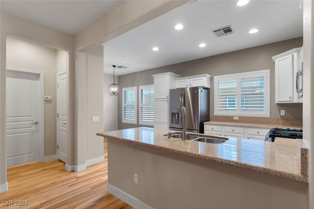 kitchen featuring visible vents, appliances with stainless steel finishes, white cabinetry, a sink, and a peninsula