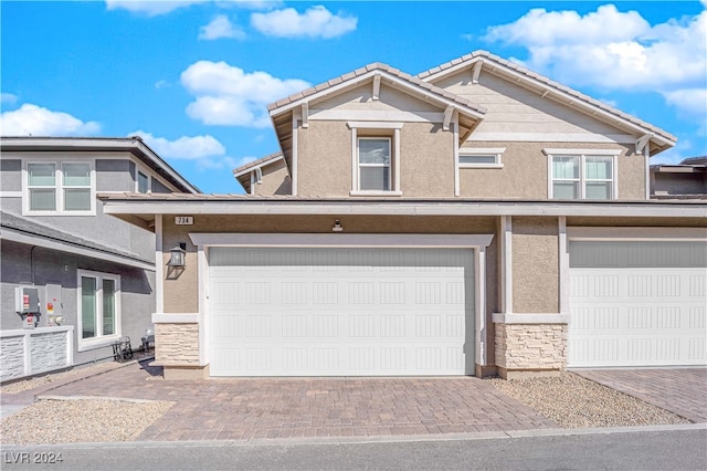 view of front of home featuring stone siding, decorative driveway, and stucco siding