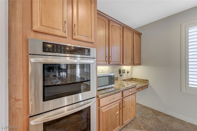 kitchen with tasteful backsplash, appliances with stainless steel finishes, light stone counters, and plenty of natural light