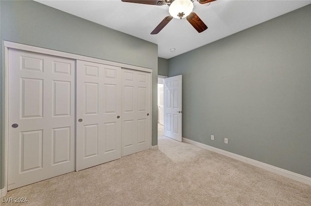 unfurnished bedroom featuring ceiling fan, light colored carpet, and a closet