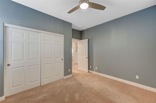 unfurnished bedroom featuring a closet, light colored carpet, and ceiling fan