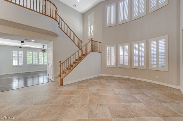 unfurnished living room featuring ceiling fan and a high ceiling