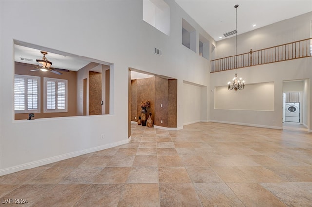 spare room with a towering ceiling, ceiling fan with notable chandelier, and washer / clothes dryer