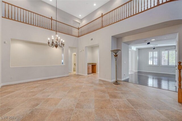 unfurnished room featuring ceiling fan with notable chandelier and a towering ceiling