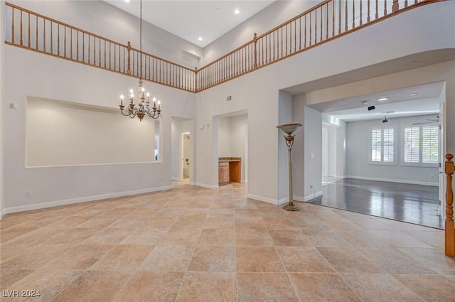 spare room with a towering ceiling and a notable chandelier