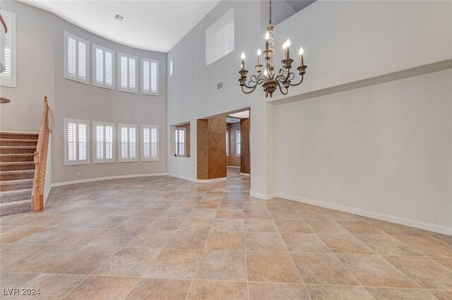 unfurnished living room featuring a high ceiling, light tile patterned floors, and an inviting chandelier