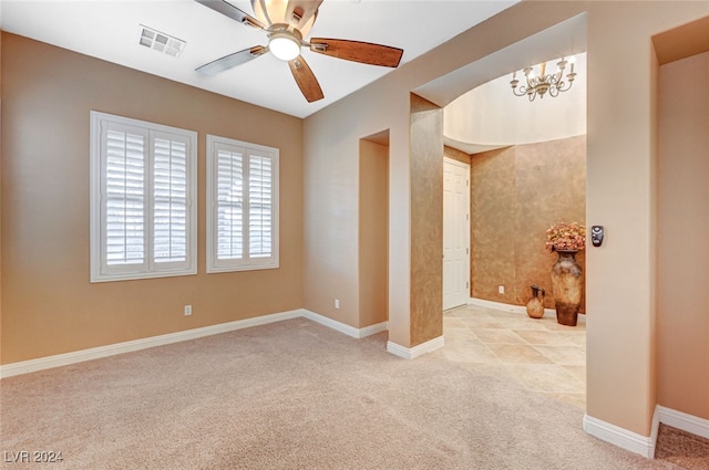 interior space with light colored carpet and ceiling fan with notable chandelier