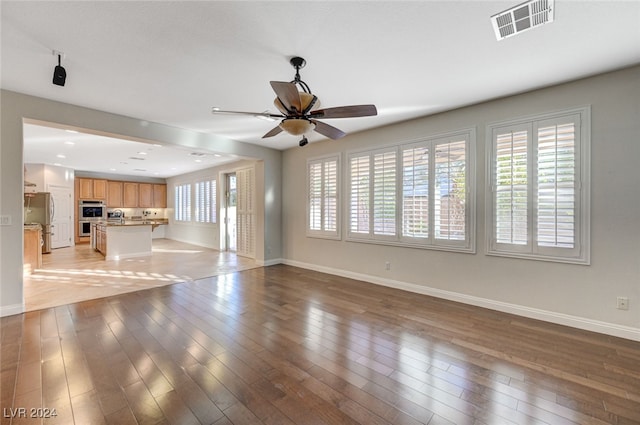 unfurnished living room featuring hardwood / wood-style floors, ceiling fan, and plenty of natural light