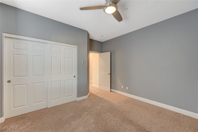 unfurnished bedroom featuring ceiling fan, a closet, and light colored carpet