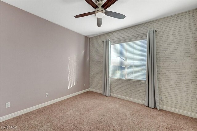 carpeted empty room with brick wall and ceiling fan