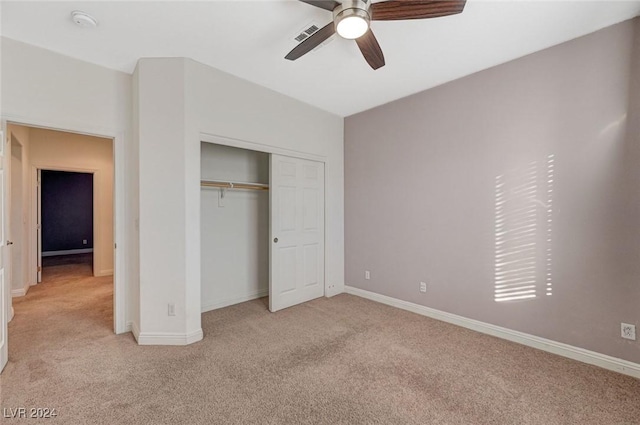 unfurnished bedroom featuring ceiling fan, light colored carpet, and a closet