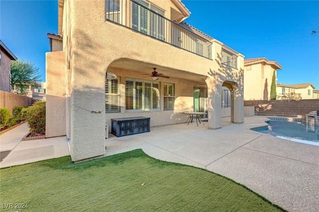 rear view of house featuring a fenced in pool, a balcony, a patio, and ceiling fan