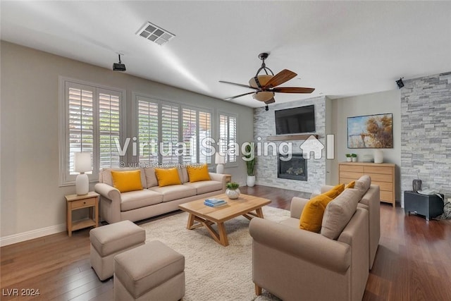 living room with ceiling fan, wood-type flooring, and a stone fireplace