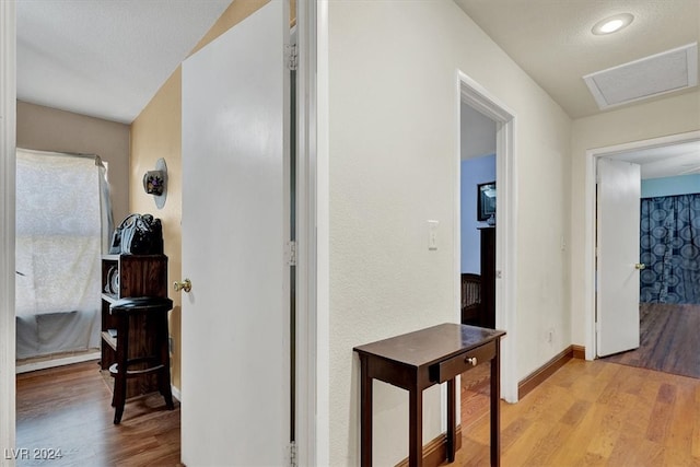 hall with light wood-type flooring and a textured ceiling