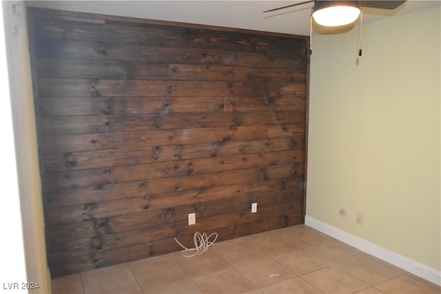 spare room featuring light tile patterned floors and wood walls