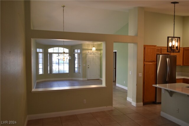 kitchen featuring stainless steel fridge, light tile patterned floors, pendant lighting, and an inviting chandelier