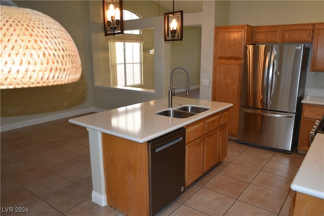 kitchen featuring a kitchen island with sink, sink, black dishwasher, decorative light fixtures, and stainless steel refrigerator