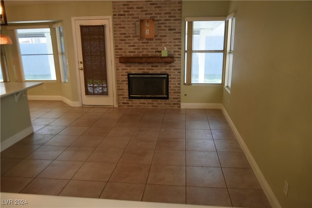 unfurnished living room featuring light tile patterned floors and a brick fireplace