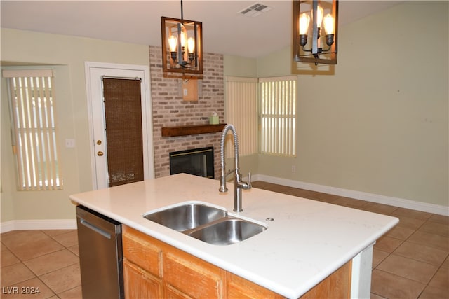 kitchen featuring dishwasher, a center island with sink, sink, light tile patterned floors, and decorative light fixtures