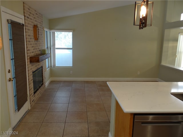 kitchen featuring a fireplace, light tile patterned floors, vaulted ceiling, and dishwasher