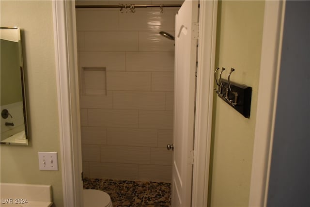 bathroom featuring a tile shower and toilet