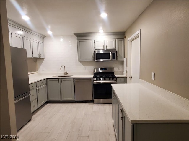 kitchen featuring light hardwood / wood-style flooring, stainless steel appliances, gray cabinetry, and sink