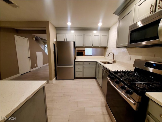 kitchen featuring sink, backsplash, gray cabinets, and stainless steel appliances