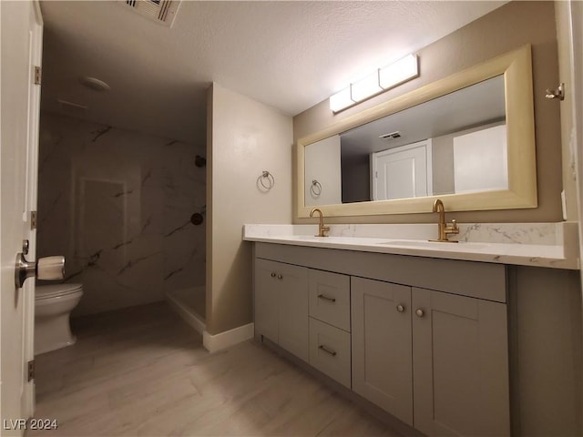 bathroom featuring hardwood / wood-style flooring, toilet, a textured ceiling, walk in shower, and vanity