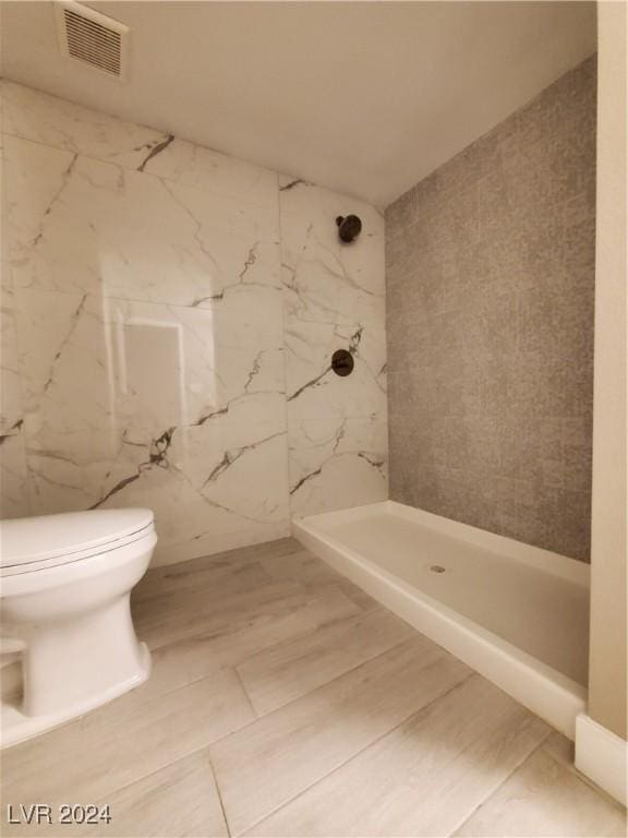 bathroom with tiled shower and toilet