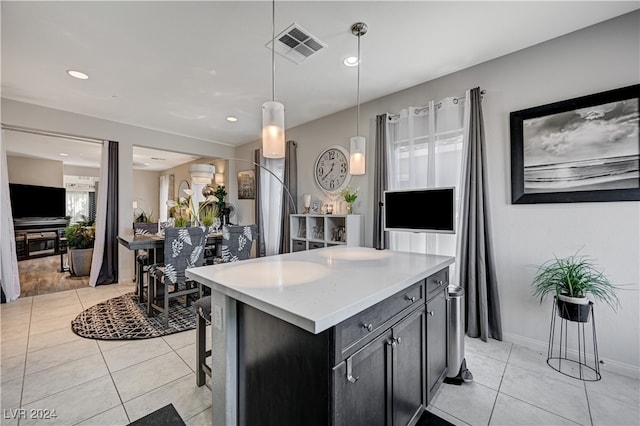 kitchen featuring hanging light fixtures, a breakfast bar area, light tile patterned floors, and a center island