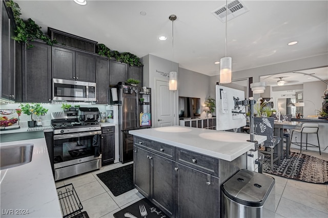 kitchen featuring light tile patterned flooring, appliances with stainless steel finishes, ceiling fan, decorative light fixtures, and a kitchen island