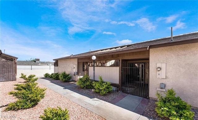 view of exterior entry with stucco siding and fence