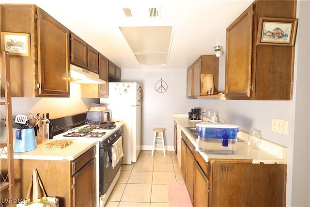 kitchen with visible vents, light tile patterned floors, light countertops, under cabinet range hood, and gas range oven